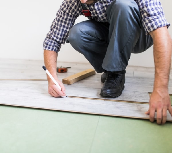 young-worker-lining-floor-with-laminated-flooring-boards
